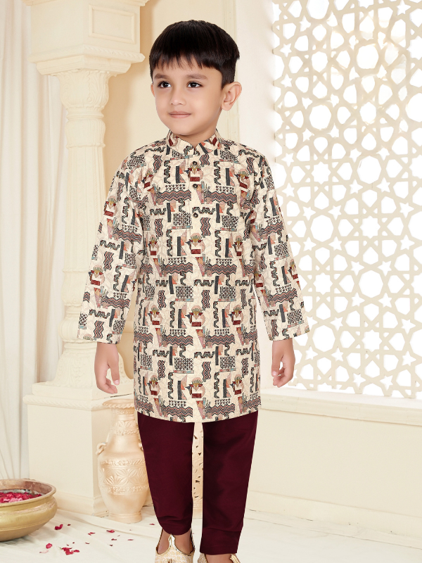 Young boy smiling and wearing a long-sleeve dusty pink kurta with a Bandhgala collar and white pajama bottoms.