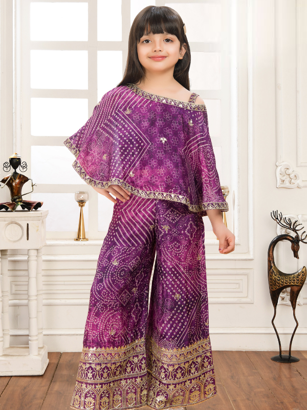 Young girl modeling a deep purple ethnic set with a Bandhani-style printed cape top and wide-leg palazzo pants with a gold embroidered border.