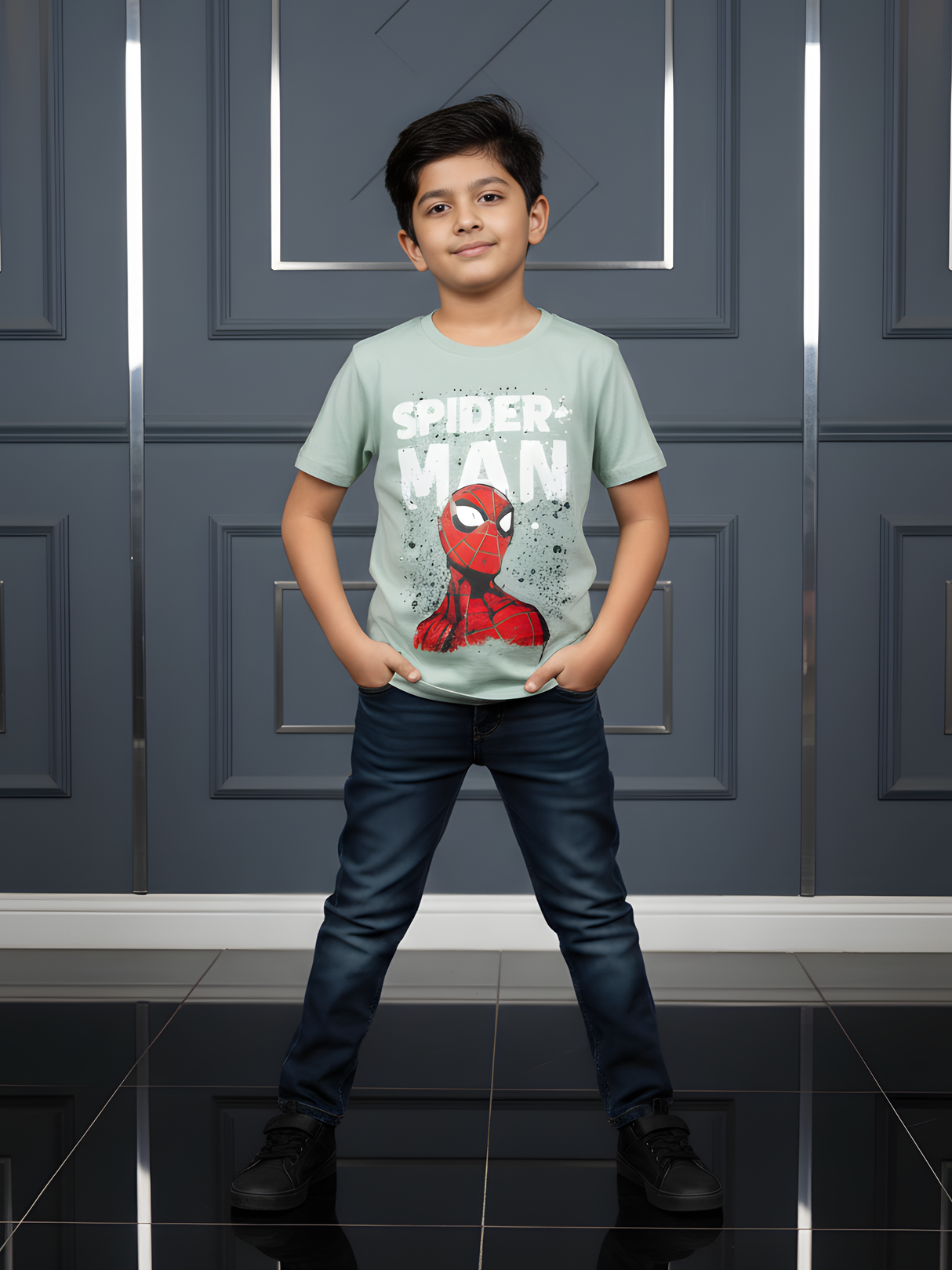 Child wearing a Spider-Man t-shirt standing in front of a gray wall.