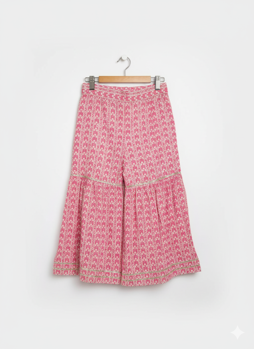 Front view of a girls' 3/4 sleeve pink and white floral-printed peplum top (kurti) with a heavily embroidered and mirror-work detailed yoke, hanging on a wooden hanger.