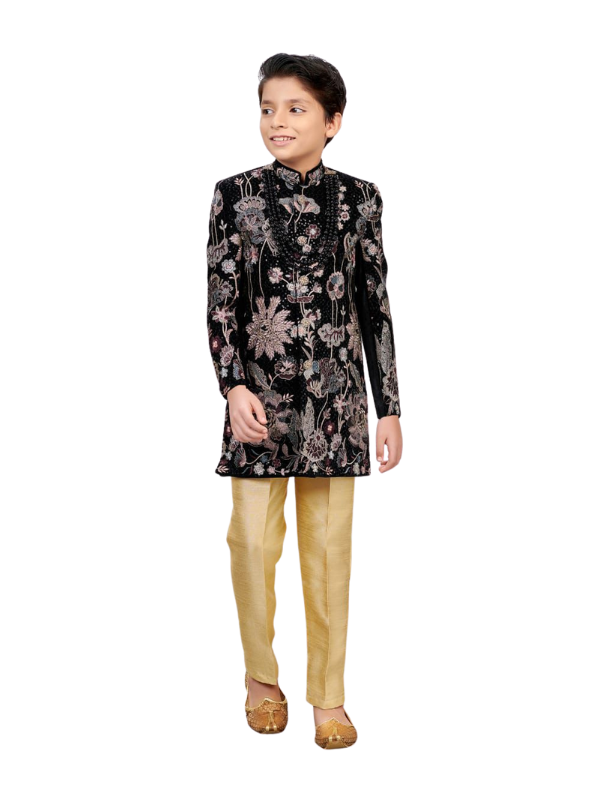 Young boy wearing a black Sherwani-style suit with all-over tonal embroidery, black beaded collar trim, and slim-fit gold shimmer trousers.