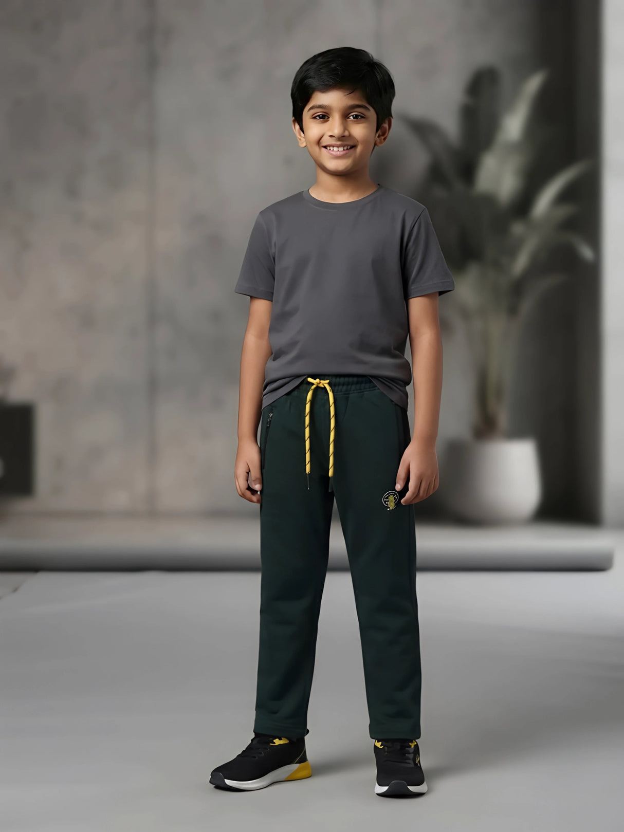 Young boy wearing dark green casual trackpants with contrast yellow drawstrings and zippered pockets