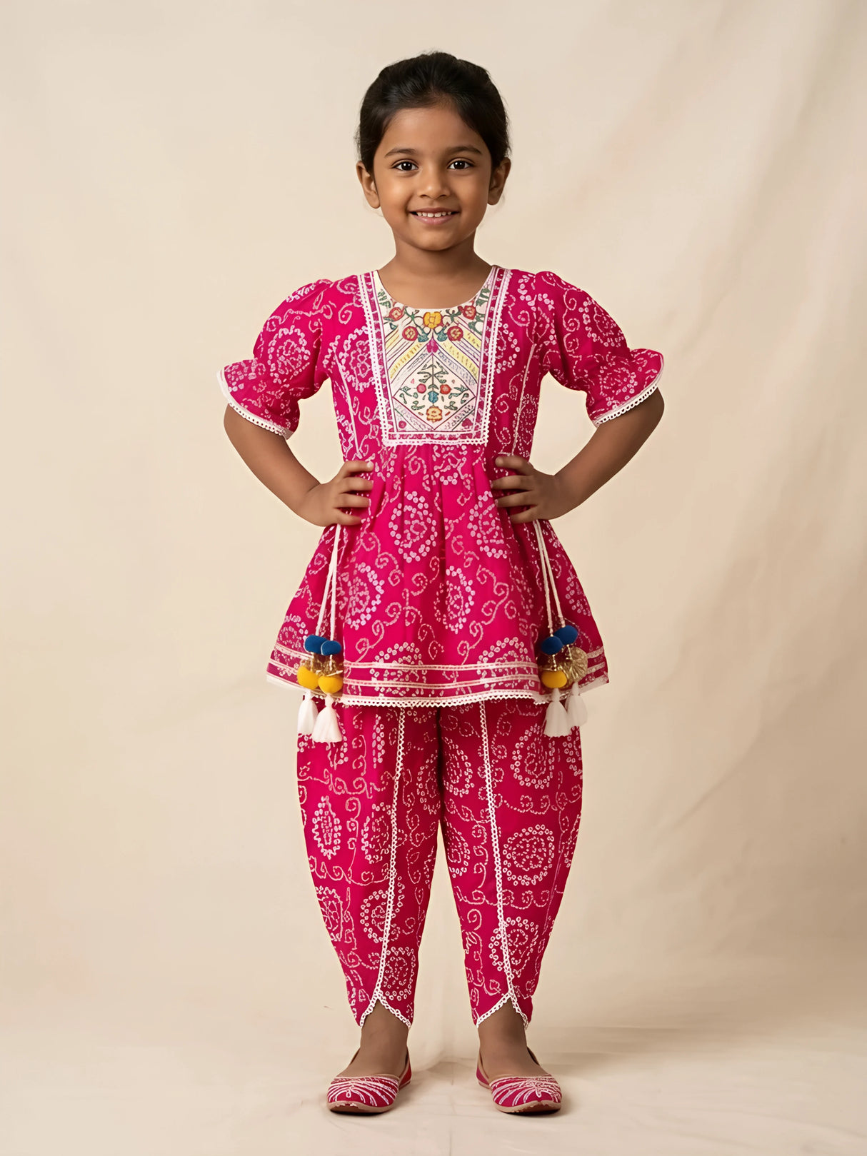 Young girl wearing a vibrant pink bandhani print kurti and matching dhoti pants set with embroidered neck yoke