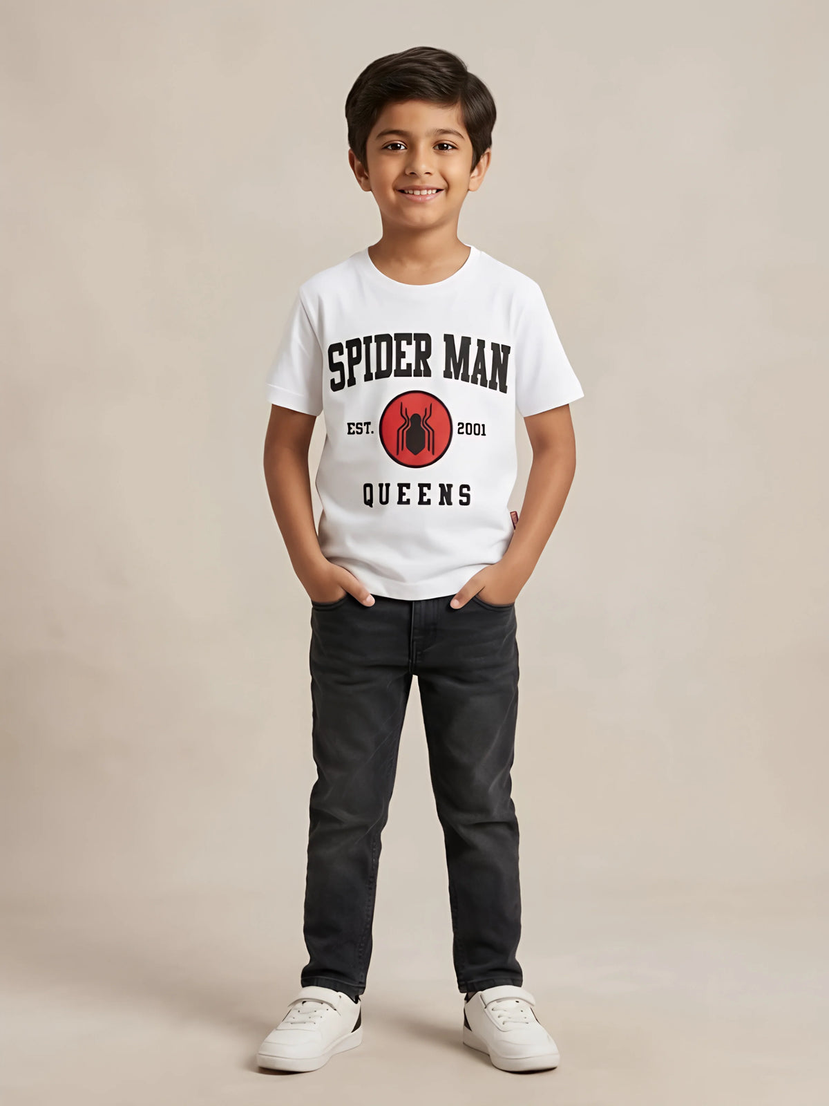 Young boy wearing a white short-sleeve graphic t-shirt with Spider-Man text and logo on the front paired with dark jeans.