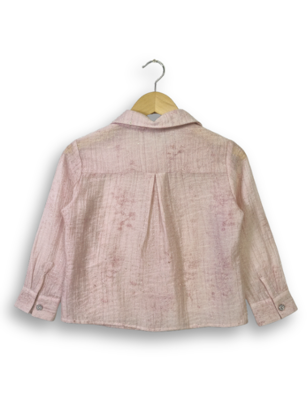 Front view of a girls' sheer peach long-sleeve button-up shirt with silver rhinestone clusters on the chest, hanging on a wooden hanger.