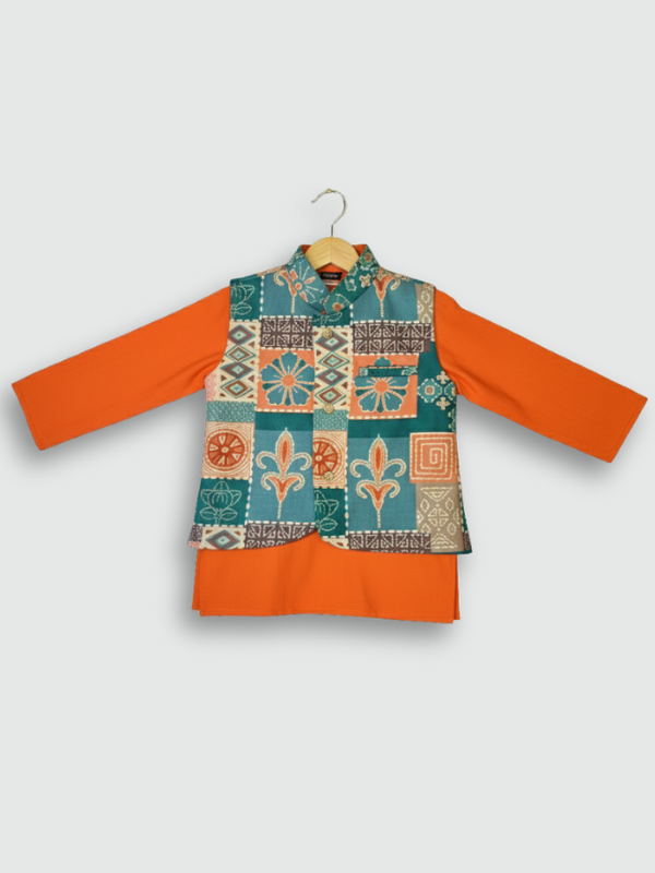 A young boy standing and smiling, wearing a bright orange long-sleeved kurta and pajama set, accessorized with a sleeveless teal, orange, and cream geometric-printed Nehru jacket.