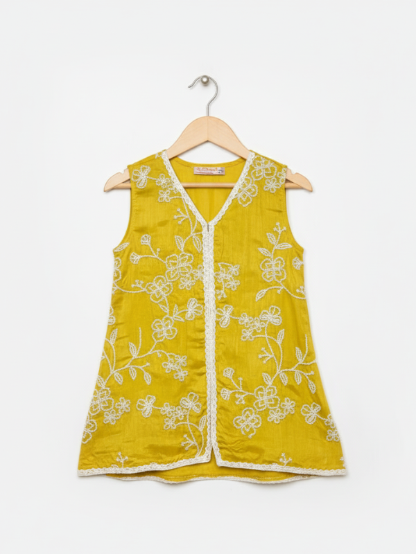 Front view of girls' wide-leg yellow palazzo pants with scattered white floral embroidery and a white lace trim on the hem, hanging on a wooden hanger.