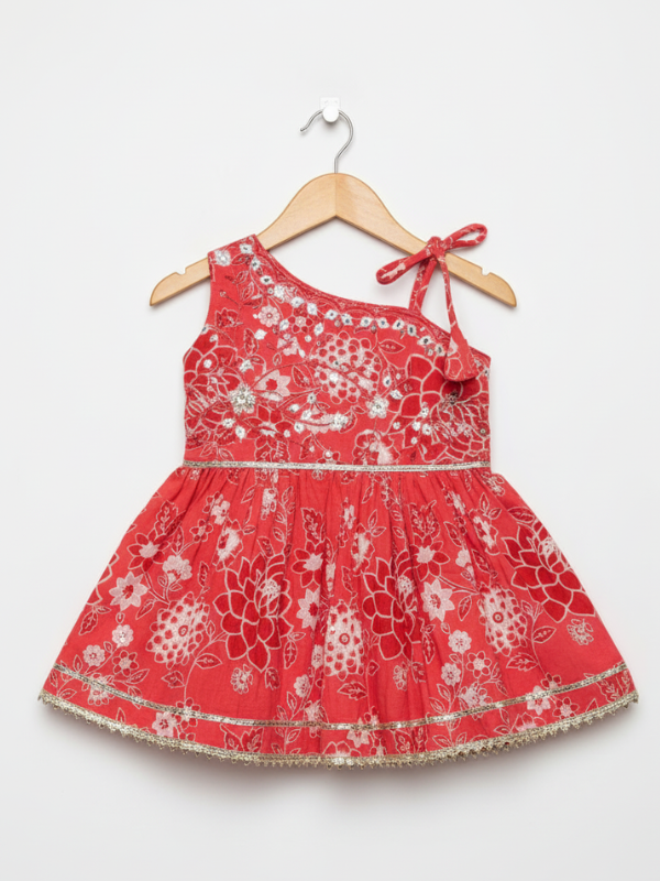 Full-length image of a young girl wearing a coral red and white printed peplum kurta with shoulder ties, wide-leg palazzo pants, and a white-to-red ombre dupatta with silver trim.