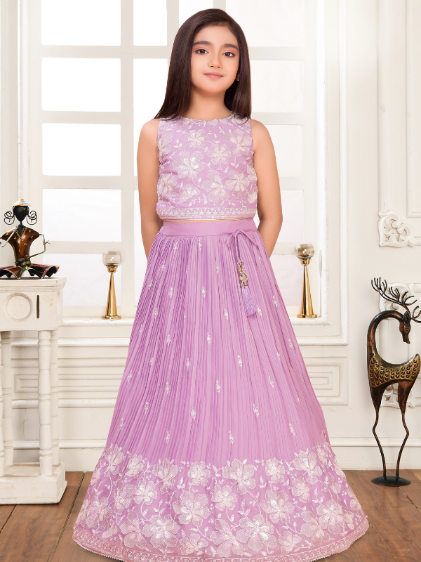 Young girl wearing a sleeveless light lavender lehenga choli set. The top is covered in white floral embroidery, and the flared skirt features fine pleats and a heavily embroidered white floral border.
