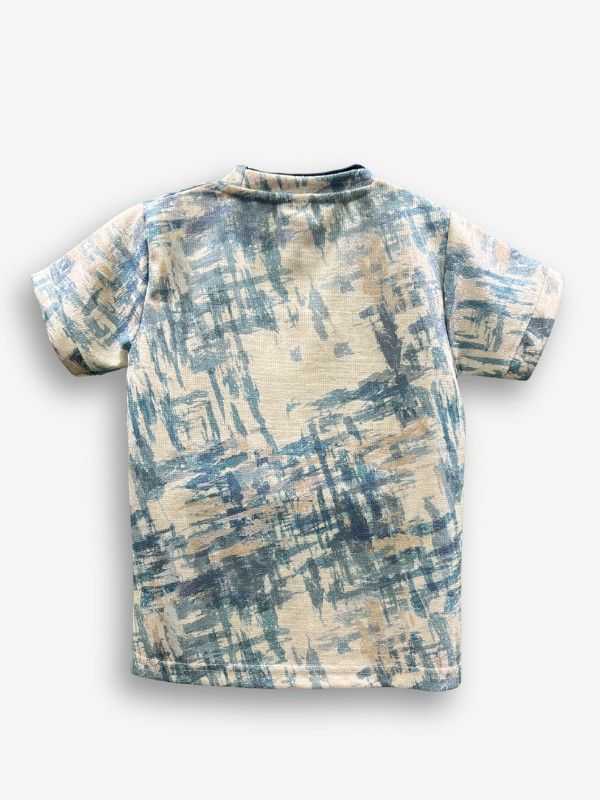 Cream/Off-white boys' short-sleeve T-shirt with an all-over blue abstract brushstroke pattern, featuring a black raised peace sign and the text "BE KIND" on the chest