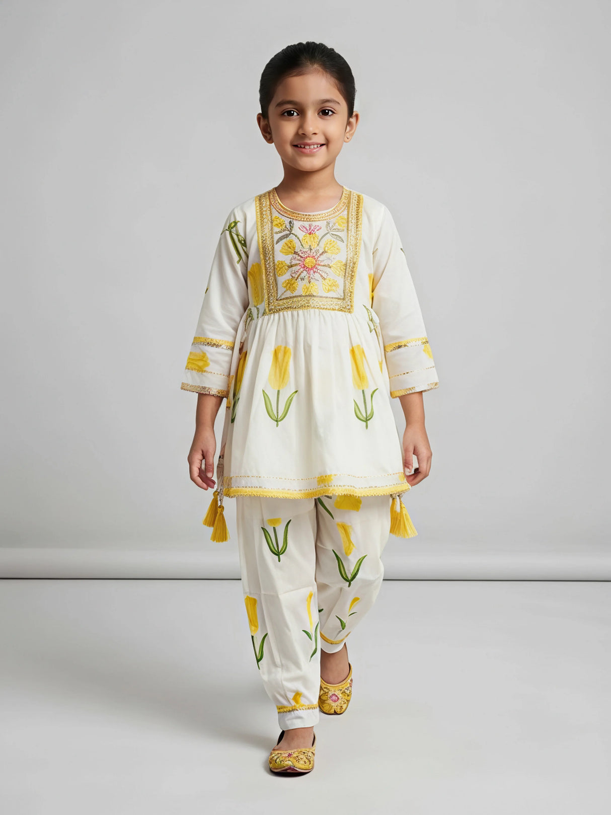 Young girl wearing a cream and yellow floral printed Patiala suit set with embroidery and side tassels