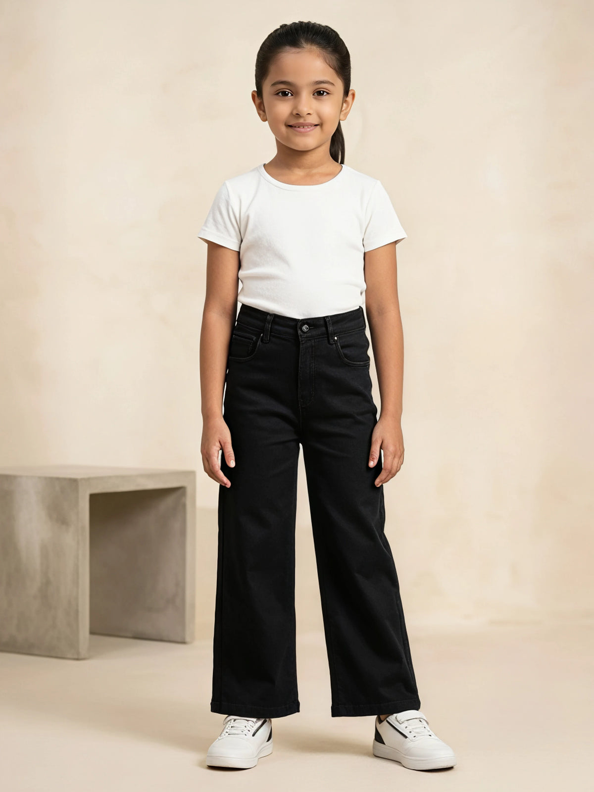 Young girl wearing black high-waisted wide-leg casual pants paired with a white t-shirt and white sneakers