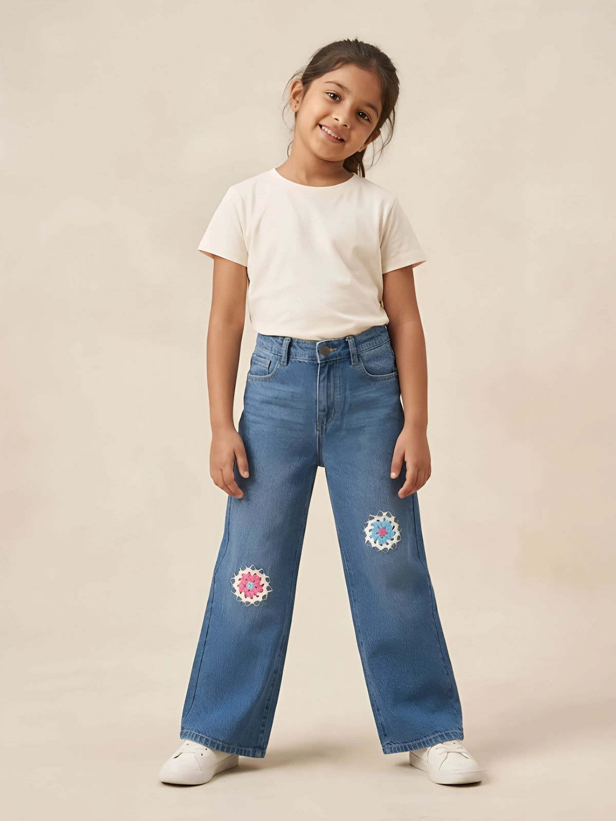 Young girl wearing light blue wide leg casual pants featuring floral crochet embroidery on knees