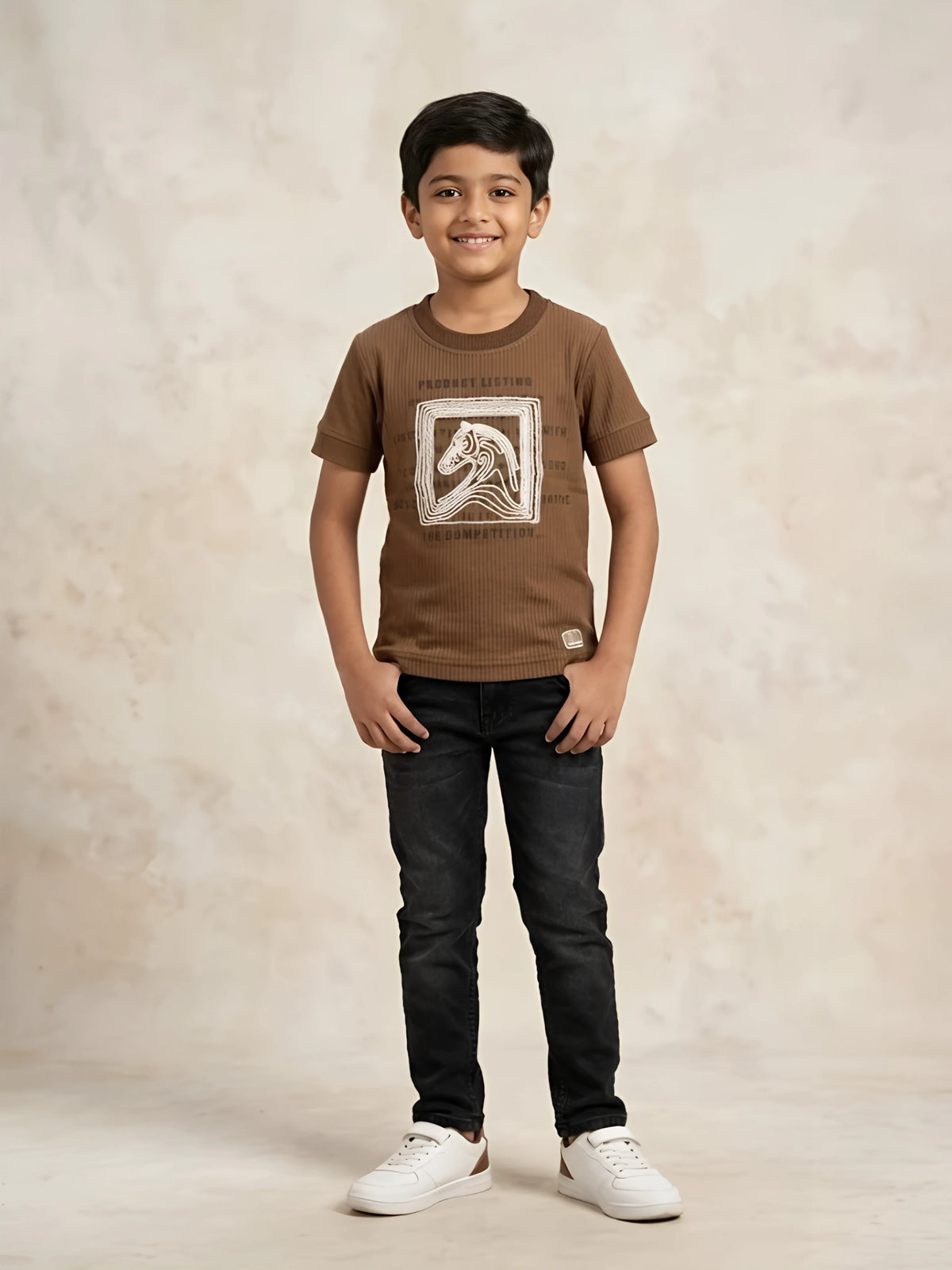 Young boy wearing a brown short-sleeve graphic t-shirt with dark jeans