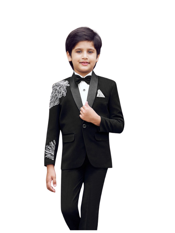Front view of a young boy wearing a black tuxedo suit with a satin shawl lapel, white shirt, black bow tie, and elaborate silver bead and sequin embroidery on the left shoulder and cuff.