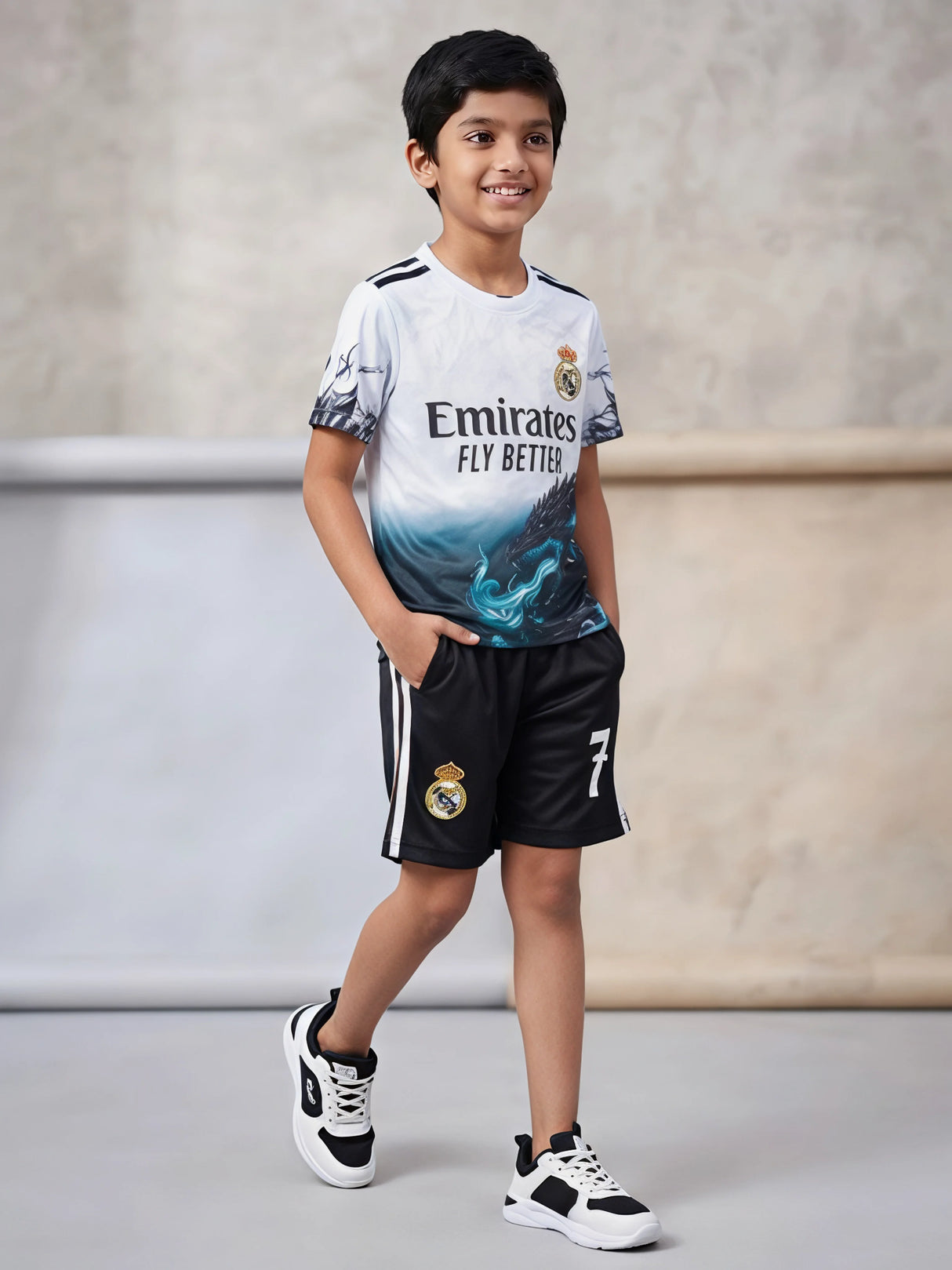 Young boy wearing a white and black sports co-ord set with graphic print t-shirt and matching striped shorts.