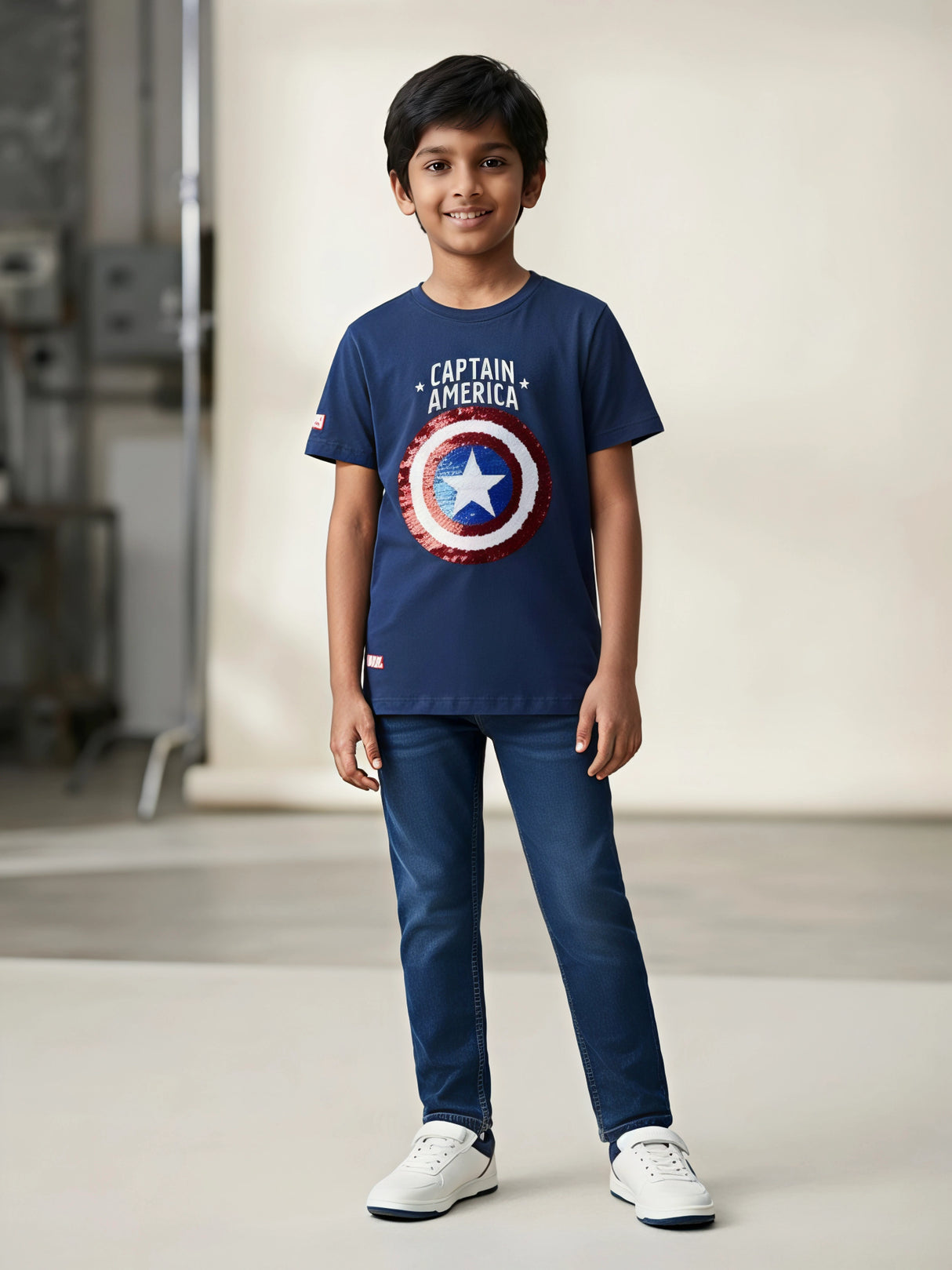 Young boy wearing a navy blue Captain America shield graphic t-shirt with jeans