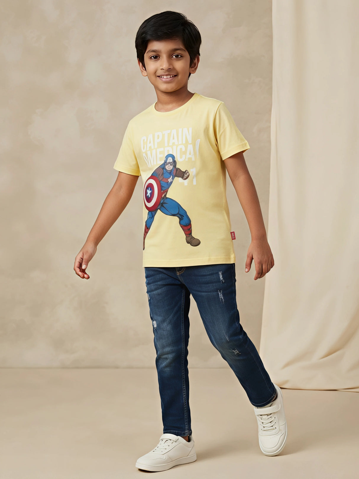 Young boy wearing a bright yellow round-neck t-shirt featuring a Captain America graphic print paired with blue jeans.