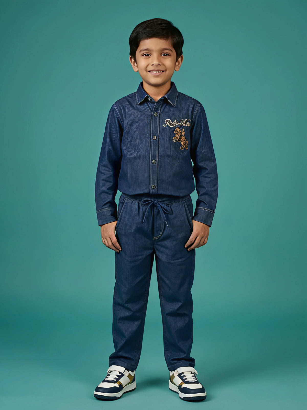 Young boy wearing a navy blue long-sleeve embroidered shirt and matching drawstring trousers co-ord set