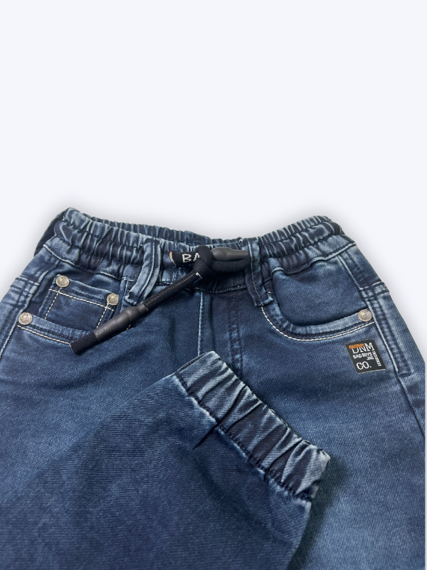 Close-up of boys' navy blue denim jogger pants with elastic waist, black drawstring, and elasticated ankle cuffs on a white background.