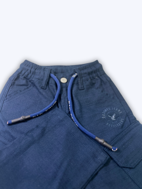 Boys' plain navy blue cargo pants made of soft fleece or knit material, hanging on a wooden hanger, showing the elastic waist and large side pockets.