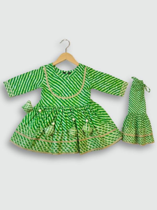 Full-length image of a young girl wearing a lime green and white floral-printed ethnic set with an embroidered peplum kurta, tiered sharara pants with a zig-zag print, and a white and green dupatta.