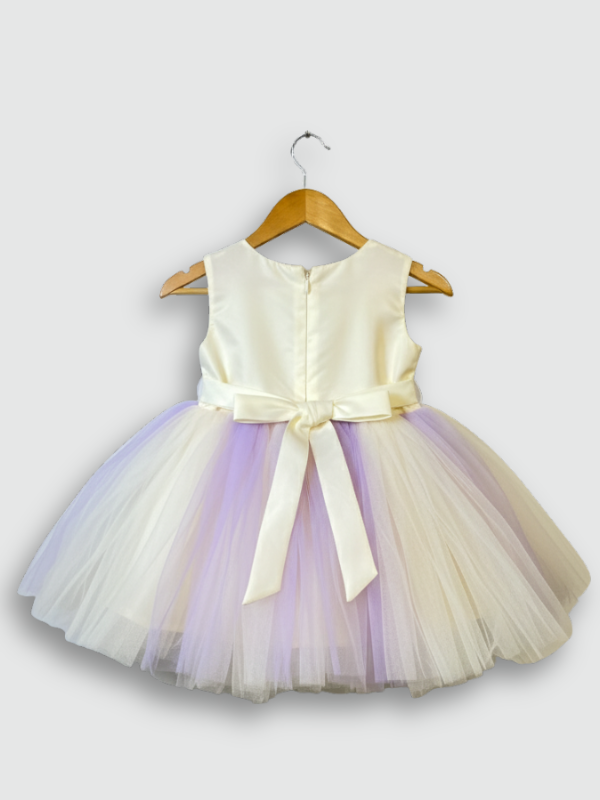 Cream girls' sleeveless party frock on a hanger, featuring a 3D flower-embellished bodice in cream and purple, and a full, layered tulle skirt with vertical lavender strips.