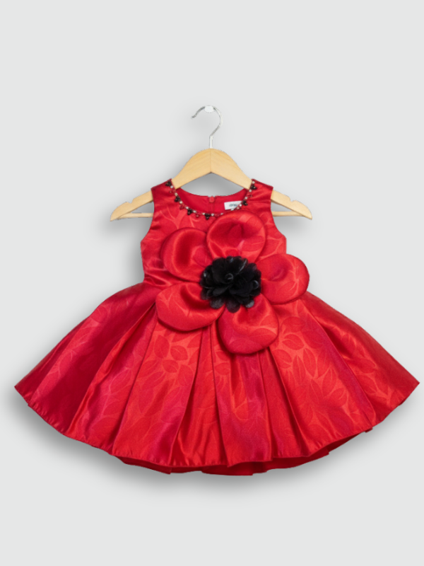 Ruby red girls' sleeveless party frock on a hanger, featuring a textured pleated skirt and a large red 3D flower appliqué with a black center on the bodice.
