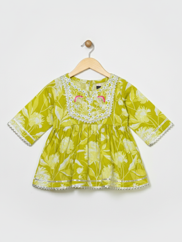 Full-length image of a young girl wearing a lime green and white floral-printed ethnic set with an embroidered peplum top, tiered gharara pants with a zig-zag print, and a white and green dupatta.