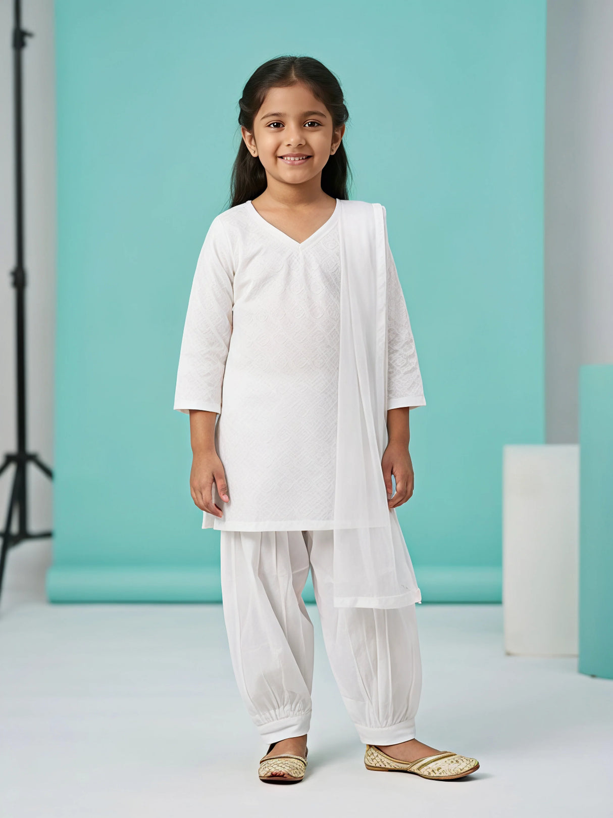 Young girl wearing a classic white textured short kurti with a pleated Patiala salwar and matching draped dupatta