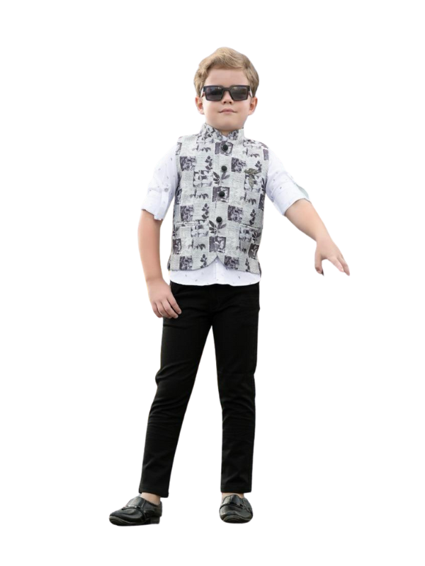 Young boy posing in a long-sleeve deep maroon velvet Indo-Western coat/sherwani with a silver embroidered crest on the shoulder, paired with white trousers and black formal shoes.