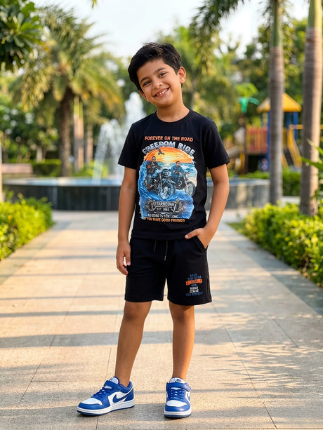 Young boy wearing a black Freedom Ride motorcycle graphic T-shirt and matching black shorts co-ord set in a park setting.