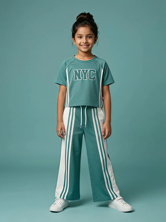Young girl wearing a sage green top with NYC print and matching striped wide-leg pants   