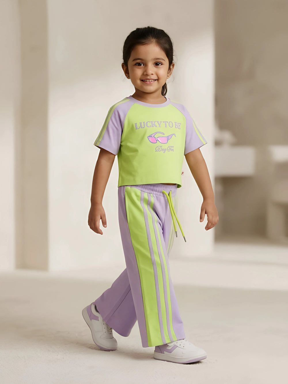 Purple and green graphic print girls coordinate set laid flat on a white background.