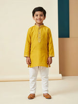 Young boy wearing a bright yellow mandarin collar kurta with white pyjamas