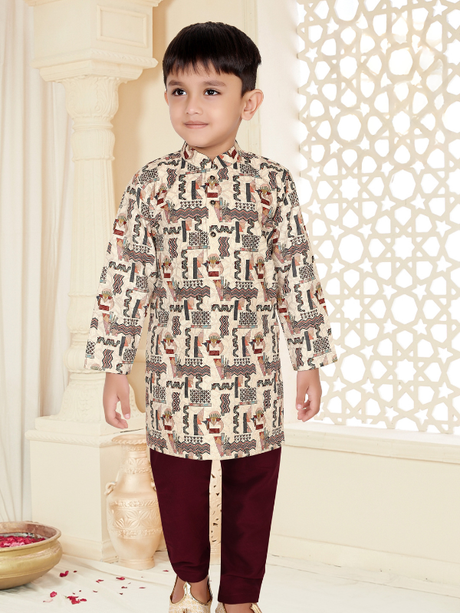 Young boy smiling and wearing a long-sleeve dusty pink kurta with a Bandhgala collar and white pajama bottoms.