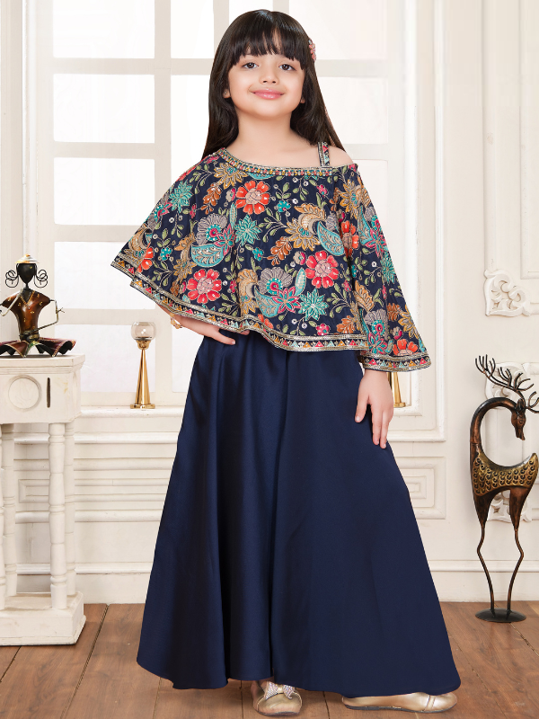 Young girl modeling a navy blue ethnic set with a short, embroidered cape top featuring bright floral patterns and full-length wide-leg palazzo pants.