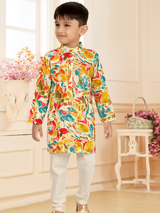 Young boy modeling a long-sleeve, cream-colored kurta with a red, yellow, and blue abstract leaf print, paired with solid white pajama pants.