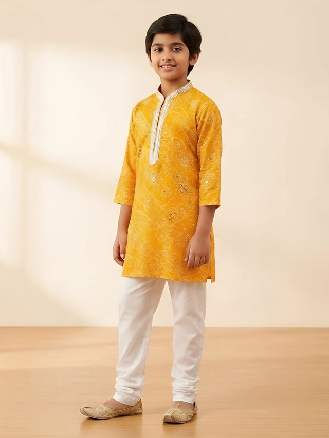 Yellow bandhani print kurta pajama set for boys with silver neck detailing.