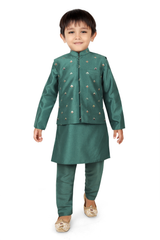 Young boy wearing a monochromatic peacock green kurta pajama set, layered with a matching long-sleeved jacket featuring small gold embroidery, and festive gold ethnic shoes.