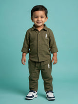 Young boy wearing an olive green textured shirt and matching trouser co-ord set with white sneakers