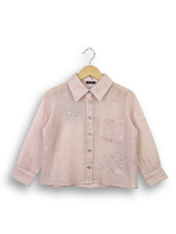Front view of a girls' sheer peach long-sleeve button-up shirt with silver rhinestone clusters on the chest, hanging on a wooden hanger.