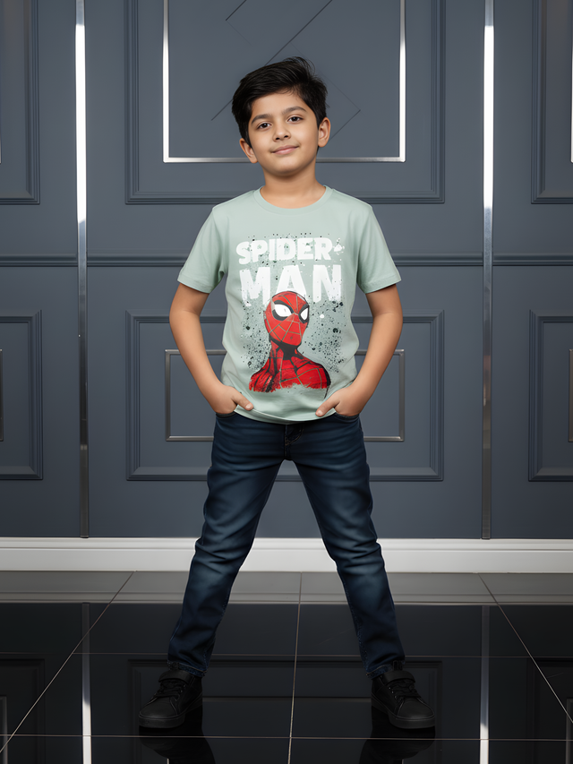 Child wearing a Spider-Man t-shirt standing in front of a gray wall.