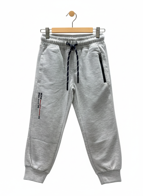 A pair of boys' light grey fleece jogger track pants with an elastic waist, navy and white contrast drawstring, ribbed ankle cuffs, and a vertical zippered pocket.