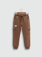 Boys' plain brown fleece cargo jogger pants with elastic drawstring waist and cuffed ankles, hanging on a wooden hanger.