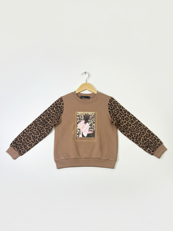 Front view of a girls' brown sweatshirt with long leopard print sleeves and a framed graphic of a girl on the chest, hanging on a wooden hanger.