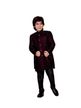 Young boy wearing a rich, royal purple velvet sherwani jacket with tonal vertical embroidery, paired with black trousers and black dress shoes.
