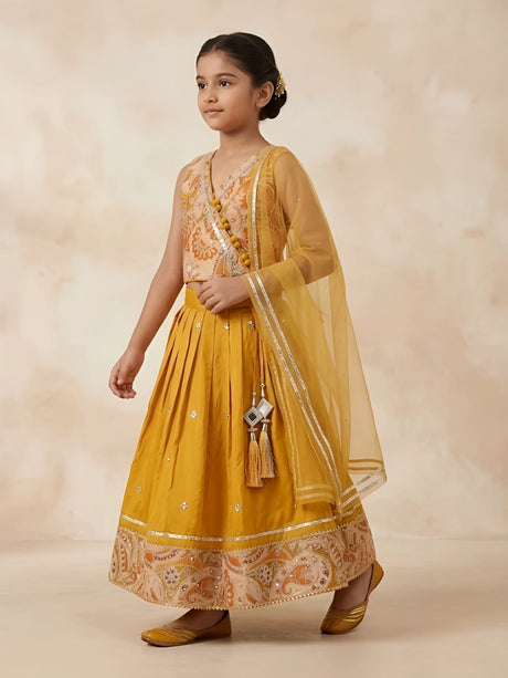 Girls wearing a yellow printed lehenga choli set with a sheer dupatta and tassel details
