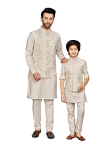 Young boy modeling a full-sleeve cream kurta set layered with a long, sleeveless jacket featuring dense tonal and gold-toned embroidery.