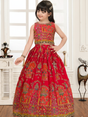 Young girl modeling a voluminous red ethnic set with an intricate multi-color print and mirror-like embellishments on the sleeveless crop top and full skirt.